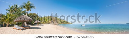 Stock-photo-tropical-beach-panorama-with-deckchairs-umbrellas-boats-and-palm-tree-57563536.jpg